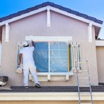 Busy House Painter Painting the Trim And Shutters of A Home.